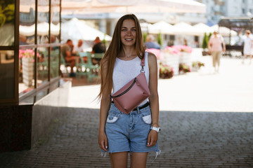 Beautiful slim girl looking at the camera and smiling. Portrait of a girl on the street.