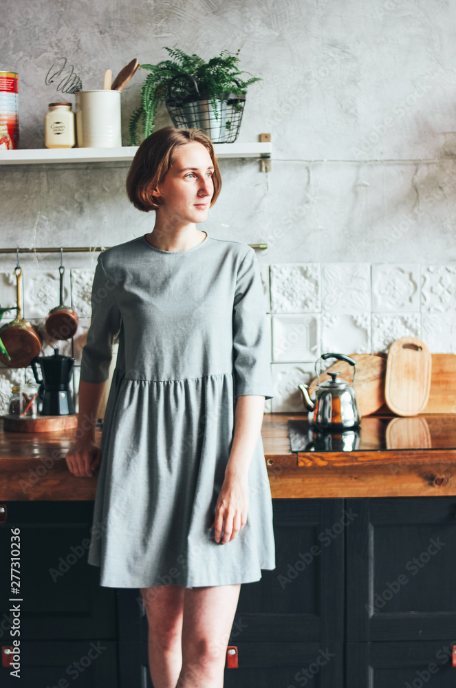 Wall mural Young woman in grey dress on the kitchen, scandinavian interior, slow life