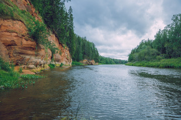City Cesis, Latvia Republic. Red rocks and river Gauja. Nature  and green trees in summer. Jul 5. 2019 Travel photo.