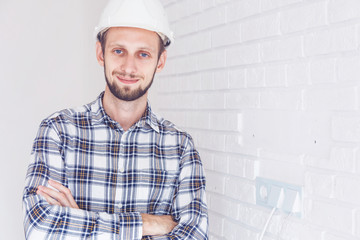 worker with yellow helmet and jeans shirt near a industrial wall