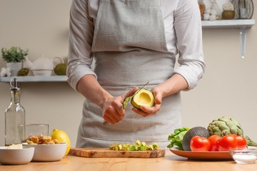Cooking. Chef slices avocado, in the process of vegetarian salad in the home kitchen. Light background. Restaurant menu, menu, recipe book. Healthy nutrition, detox