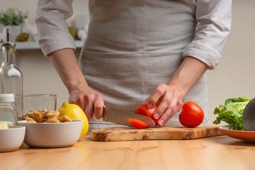 Cooking tasty and healthy food. Cooks cut tomato for salad, concept of tasty and healthy food,...
