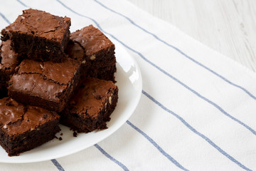 Homemade chocolate brownies on a white plate, side view. Close-up. Copy space.