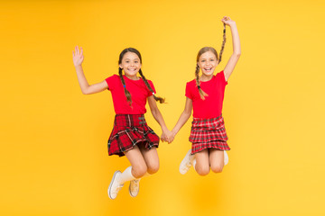 Join celebration. Kids girl wear checkered dresses. National holiday. School uniform. Scottish style. Cheerful friends schoolgirls jumping yellow background. Celebrate holiday. Scottish holiday