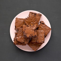 Top view, homemade chocolate brownies on a pink plate on a black background. From above, overhead, flat lay. Close-up.