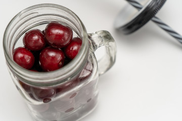 Cherries in a glass mug for coctails on the white table. Vitamine fresh food for healthy lifestyle.