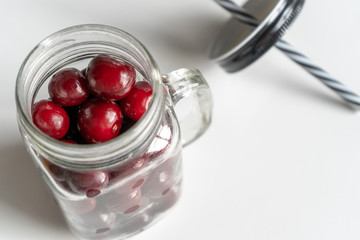Cherries in a glass mug for coctails on the white table. Vitamine fresh food for healthy lifestyle. Close-up