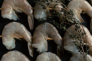 Sprigs of thyme on uncooked shrimp skewers