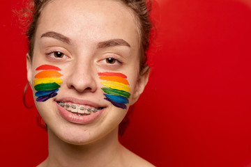 Girl with pride flag painted on her cheeks smiling