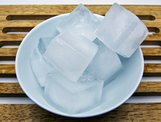 Ice cubes in a ceramic jar, wooden table, white background  