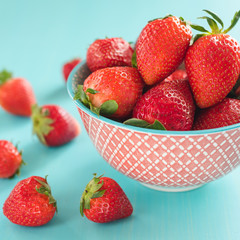 colorful ripe strawberries in a bright bowl on a blue background