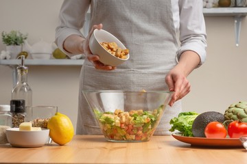 Cooking tasty and healthy food.Povar sprinkles breadcrumbs for salad, the concept of tasty and wholesome food, diet, vegetarian food, detox. On a light background, the concept of tasty food