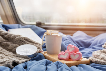 A cup of hot coffee with marshmallow near the window in the caravan camping car in the rain...