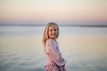 portrait of a happy cute blonde girl 5 years old, child on the seaside on a summer evening