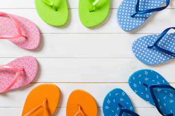 a lot of flip flop colored sandals, summer vacation on wooden background, copy space top view
