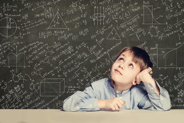 Cute smart child student on blackboard background with science formulas. Learning science concept.