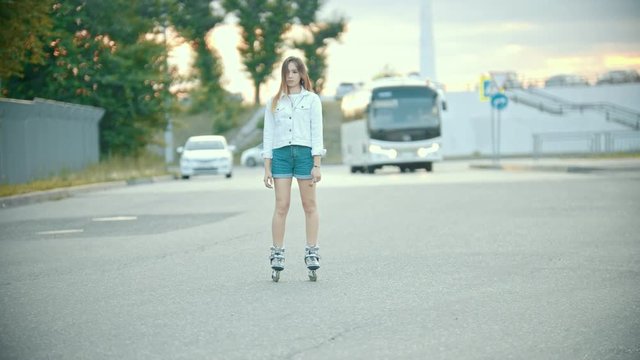 A shy teenage girl in rollerblades standing on the road