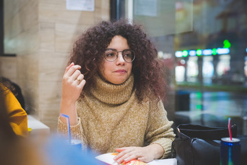 young curly woman eating in fast food with friends