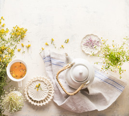 Herbal tea setting with fresh medical herbs , teapot and cup of tea. Saint-John's-wort herbs and flowers on white table background, top view. Herbal medicine. Natural dietary supplement