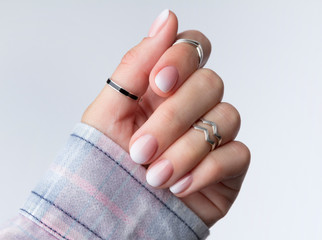 Beautiful woman's hands with ombre gradient nail design on the light gray background. © Darya Lavinskaya