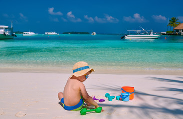 Three year old toddler boy playing with beach toys on beach.  Summer family vacation at Maldives.