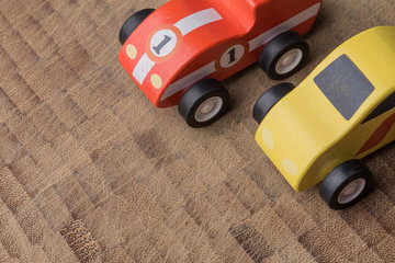 Yellow and red tony vintage toy cars racing on a wooden background