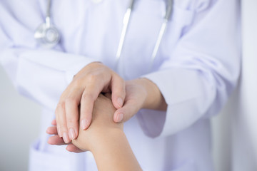 The friendly doctor's hands hold the patient's hands to encourage and care for trust