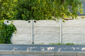 A fence made of grey concrete blocks with decorative greenery