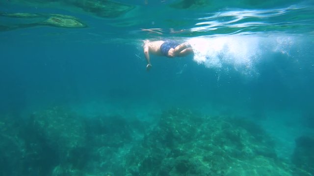 Man swimming underwater and rocky coast with beach, Mediterranean sea, Spain, Costa Brava, Catalonia, Calella de Palafrugell