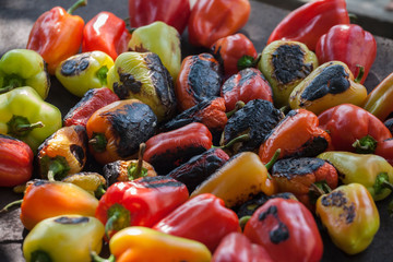 View from above of colorful red, green and yellow stuffed veggy savory bell peppers grilling on a BBQ with glowing hot coals