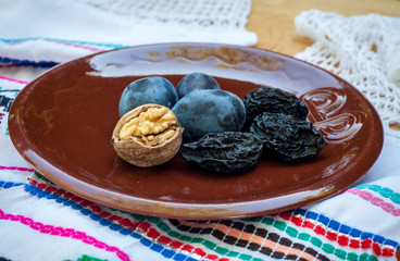 Fresh and dried prunes whit walnuts on plate. Natural food. Outdur composition. Close up.