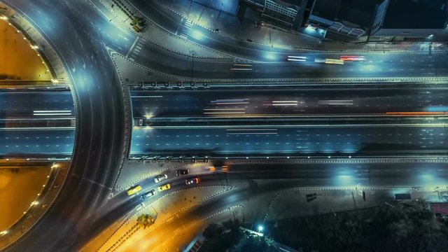 timelapse of night city traffic on 4-way stop street intersection circle roundabout in bangkok, thailand. 4K UHD horizontal aerial view.