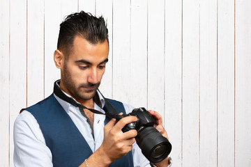 Young Arabian man using holding his camera ready to shoot, isolated