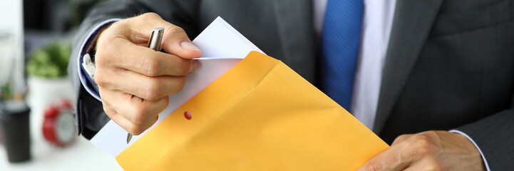 Clerk in suit and tie at workplace packing envelope unpacking envelope with important documentation
