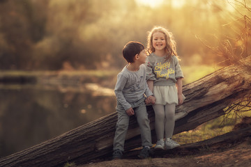 boy and girl sitting on the old log in the spring park together