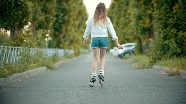 A teenage girl in rollerblades skating on the empty road