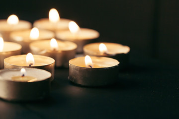 Burning candle on table in darkness, space for text. Funeral symbol
