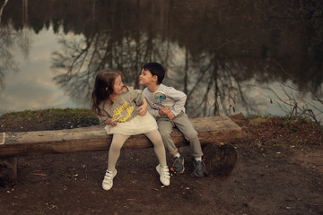boy with lollipop trying to kiss girl, sitting on the wooden bench in the park