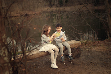 kids with lollipops talking in the park, sitting on the wooden bench