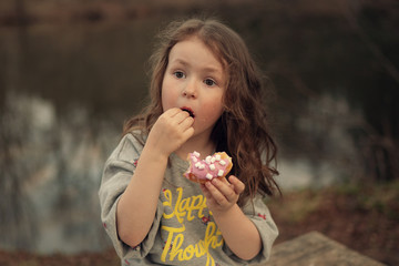 cheerful girl eating doughnut outdoors