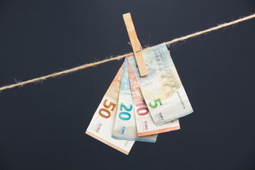 Dinero en billetes de euro, colgados por pinzas de madera en una frágil cuerda.