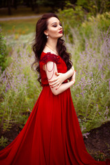 Portrait of a young brunette woman in a red dress with a train