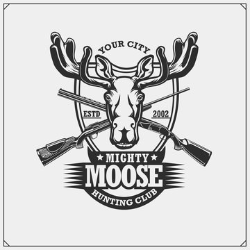 Hunting club emblem with moose or elk and crossed rifles.