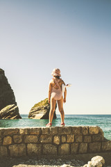 Girl child in a bathing suit standing on the beach. Montenegro beach.