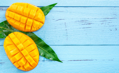 Fresh chopped mango with green leaves on bright blue color timber background. Above Top view, flat...