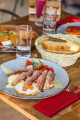 Montenegro breakfast in the restaurant. Fried eggs with bacon, pancakes and sandwiches.