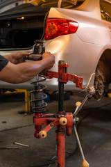 Mechanic Changing Car Absorber With Red Machine In Auto-Repair Service.