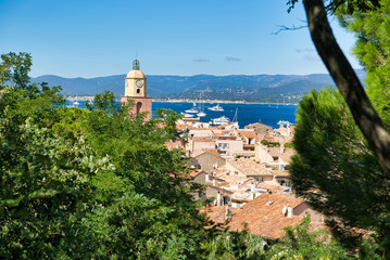 Fototapeta na wymiar View of the hill on Saint-Tropez, the roofs of houses, the chapel of St. Anne, yachts in the bay. Commune in southeastern France in the region of Provence, Alpes - Cote d'Azur, France