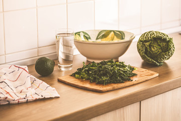 Cooking green salad from kale and avocado in the kitchen.