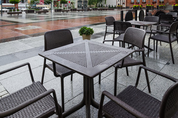 Fototapeta na wymiar A CITY IN THE RAIN - Wet tables and cafe chairs on the town hall square